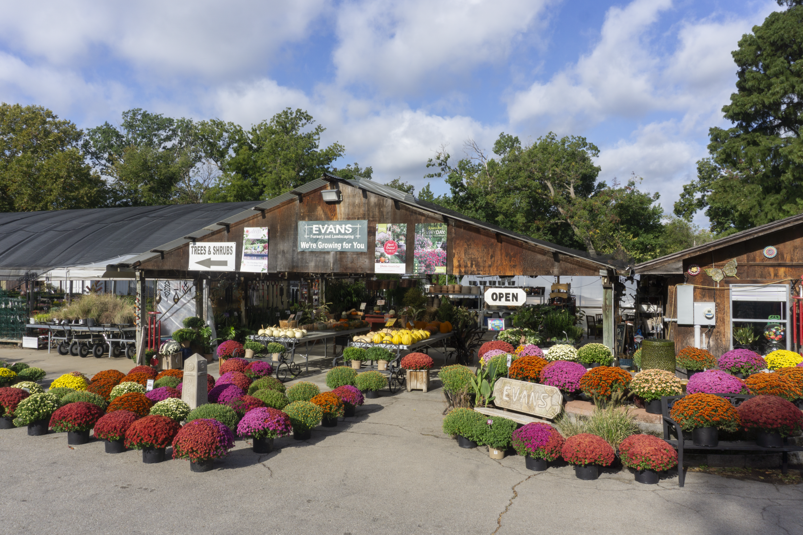 Evans Nursery, Greenhouse, and Garden Supplies in Bartlesville, OK.  External image of front of building featuring the retail shop, the covered retail area, greenhouse, and outdoor plants, imported clay pots, fountains, and water features